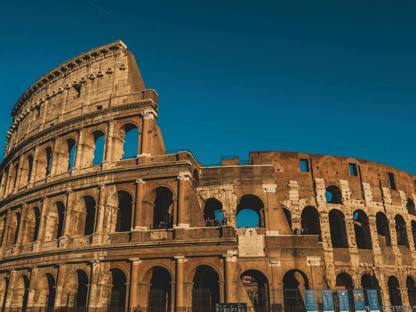 The Colosseum in Rome, Italy, under a clear blue sky, showcasing the ancient Roman amphitheater's iconic arches and historic architecture.